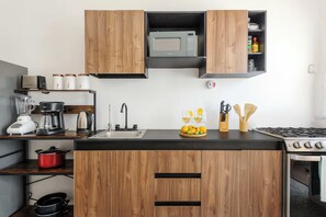 A modern kitchen with wooden cabinets, a microwave, a stove, a sink, and various kitchen appliances.