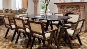 Un coin repas avec une table ronde, des chaises et un miroir décoratif.