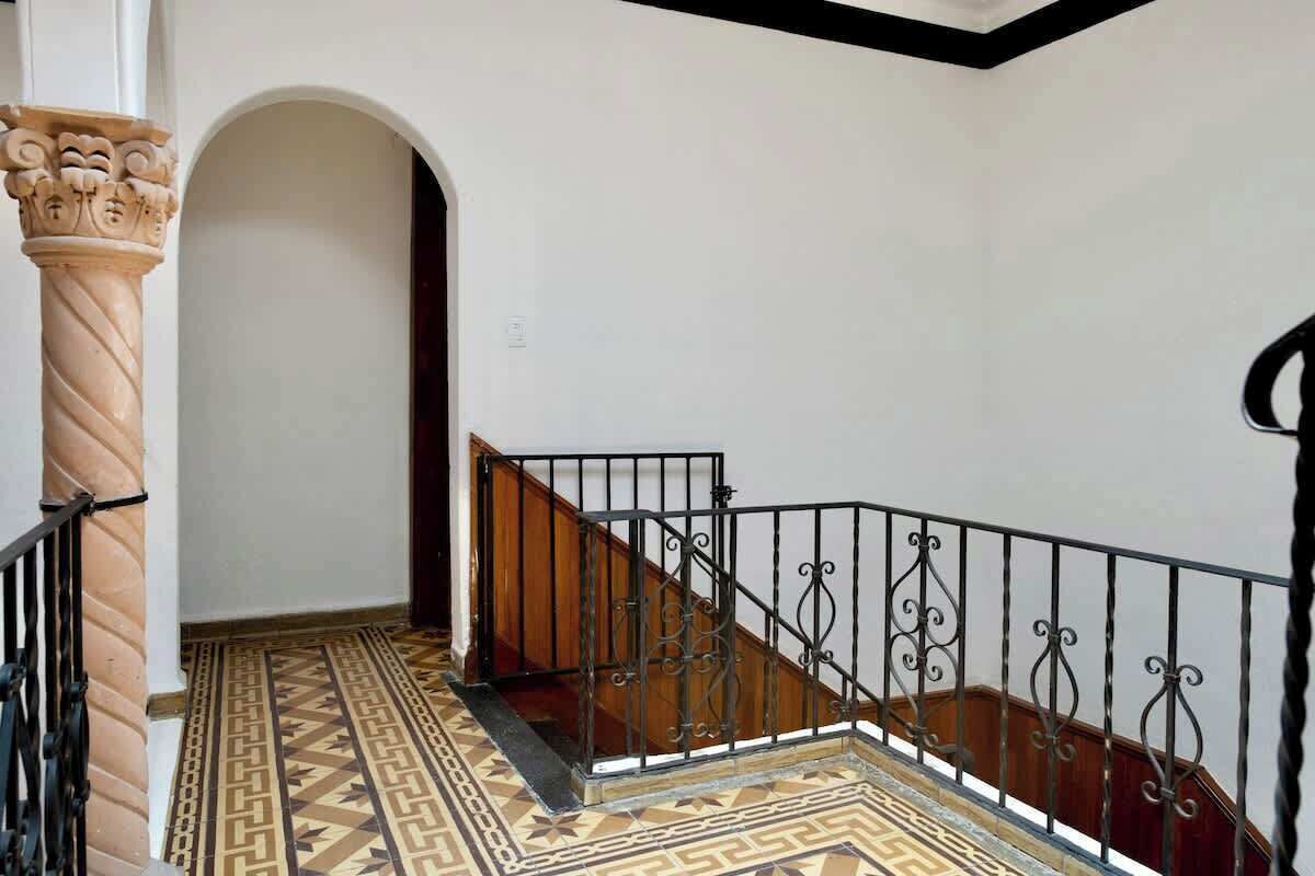 A staircase with ornate metal railings and patterned floor tiles.