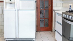 Une cuisine avec un réfrigérateur blanc, une porte en bois et une cuisinière.