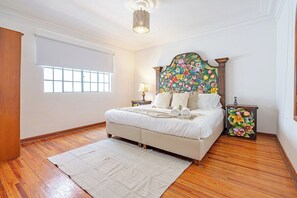 A bedroom with a large bed, a window, a wooden floor, and a decorative headboard. - Beautiful house in Condesa with 2 terraces and 8bd (Ciudad de México)