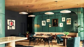 Een modern interieur met een ronde houten tafel, zitplaatsen en kunst aan de muren.