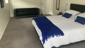 Un dormitorio con una cama, un sofá, una mesita de noche y un espejo.