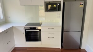 Una cocina moderna con armarios blancos, horno integrado, microondas y refrigerador de acero inoxidable.