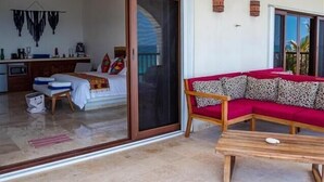 A room with a bed, a sofa, a table, and a sliding glass door leading to a balcony. - Casa Roca Chaac - Whole House (Isla Mujeres)