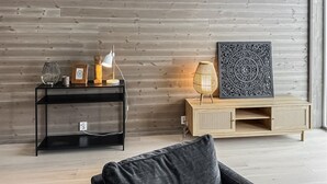 A modern living room with a wooden wall, a black console table, a wooden cabinet, and a grey sofa. - Awesome apartment in Geilo with sauna (Geilo)