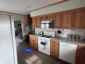A kitchen with wooden cabinets, a stainless steel microwave, a gas stove, and a dishwasher. - Quiet Country Ranch/Hunters Welcome/Peaceful ranch home with plenty of room    (Moran)
