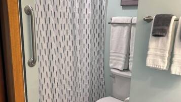 Une salle de bain avec un rideau de douche, des toilettes et un porte-serviettes avec des serviettes.