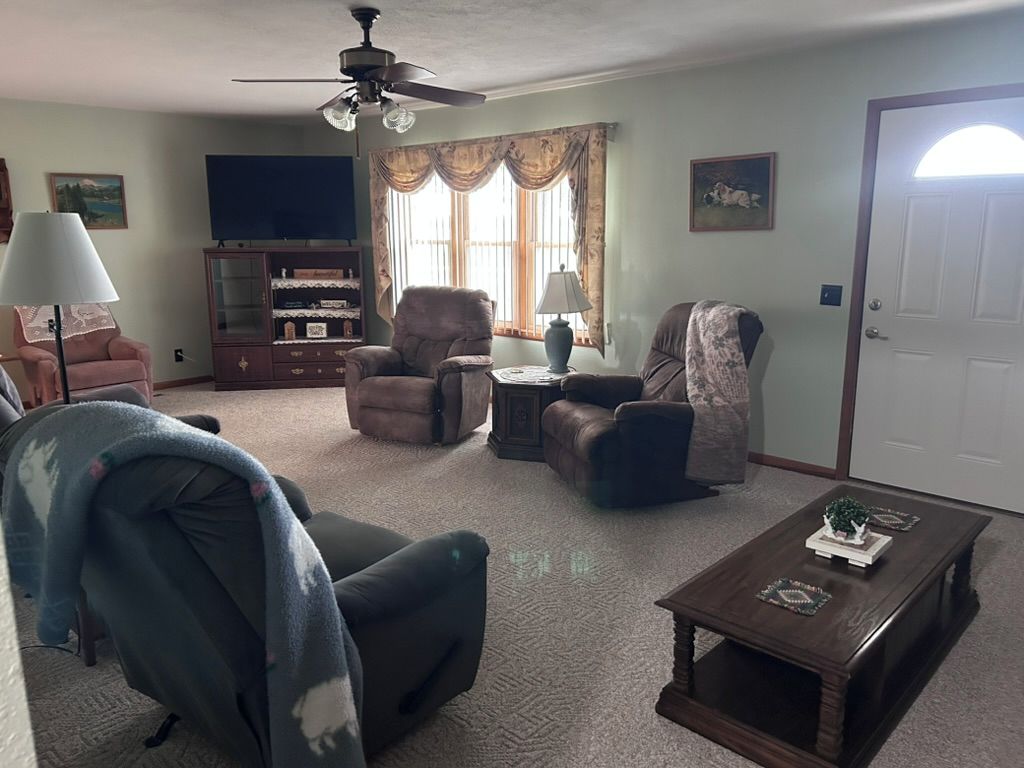 Una sala de estar con ventilador de techo, televisor, chimenea y una mesa de centro.