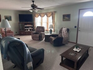 A living room with a ceiling fan, a television, a fireplace, and a coffee table. - Quiet Country Ranch/Hunters Welcome/Peaceful ranch home with plenty of room    (Moran)