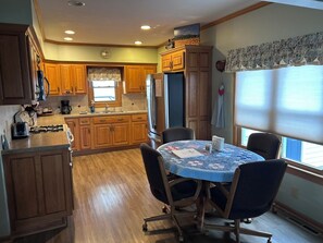A kitchen with wooden cabinets, a dining table with chairs, and a window with blinds. - Quiet Country Ranch/Hunters Welcome/Peaceful ranch home with plenty of room    (Moran)