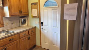 A kitchen with wooden cabinets, a stainless steel refrigerator, a microwave, and a white door.