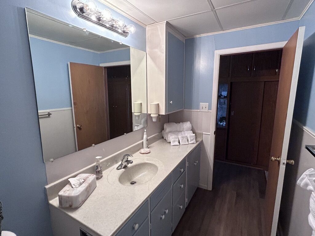 A bathroom with a large mirror, a sink, and a cabinet.