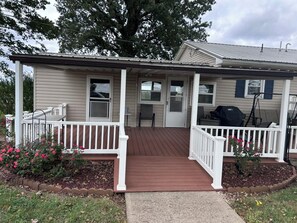A single-story house with a front porch, a covered area, and a small garden with flowers. - Quiet Country Ranch/Hunters Welcome/Peaceful ranch home with plenty of room    (Moran)