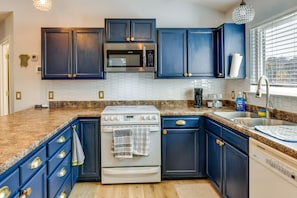 A modern kitchen with dark blue cabinets, a white stove, and a stainless steel microwave. - Peaceful Troutman Home: 5 Mi to Lake Norman! (Troutman)