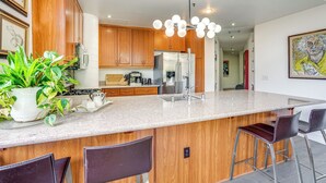 Una cocina moderna con armarios de madera, un refrigerador de acero inoxidable y una encimera de granito.