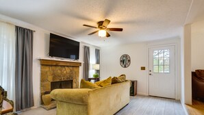 A living room with a stone fireplace, a sofa, a television, and a ceiling fan. - 1 Mi to Lake Allatoona: Family Home on Farm! (Acworth)