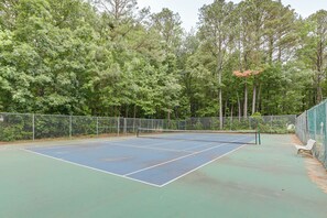 An outdoor tennis court surrounded by trees.