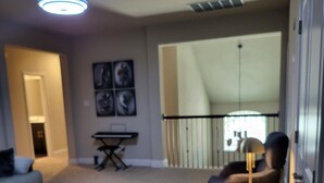 A living room with a sofa, coffee table, and a chair with a side table. There is a dining table with chairs, a ceiling light, and a window with blinds. - Unique and Stylish Modern House  (Midlothian)