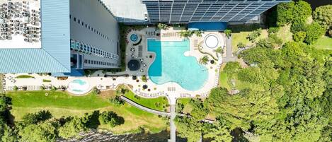 An aerial view of a hotel with a swimming pool, a dock, and a parking area.