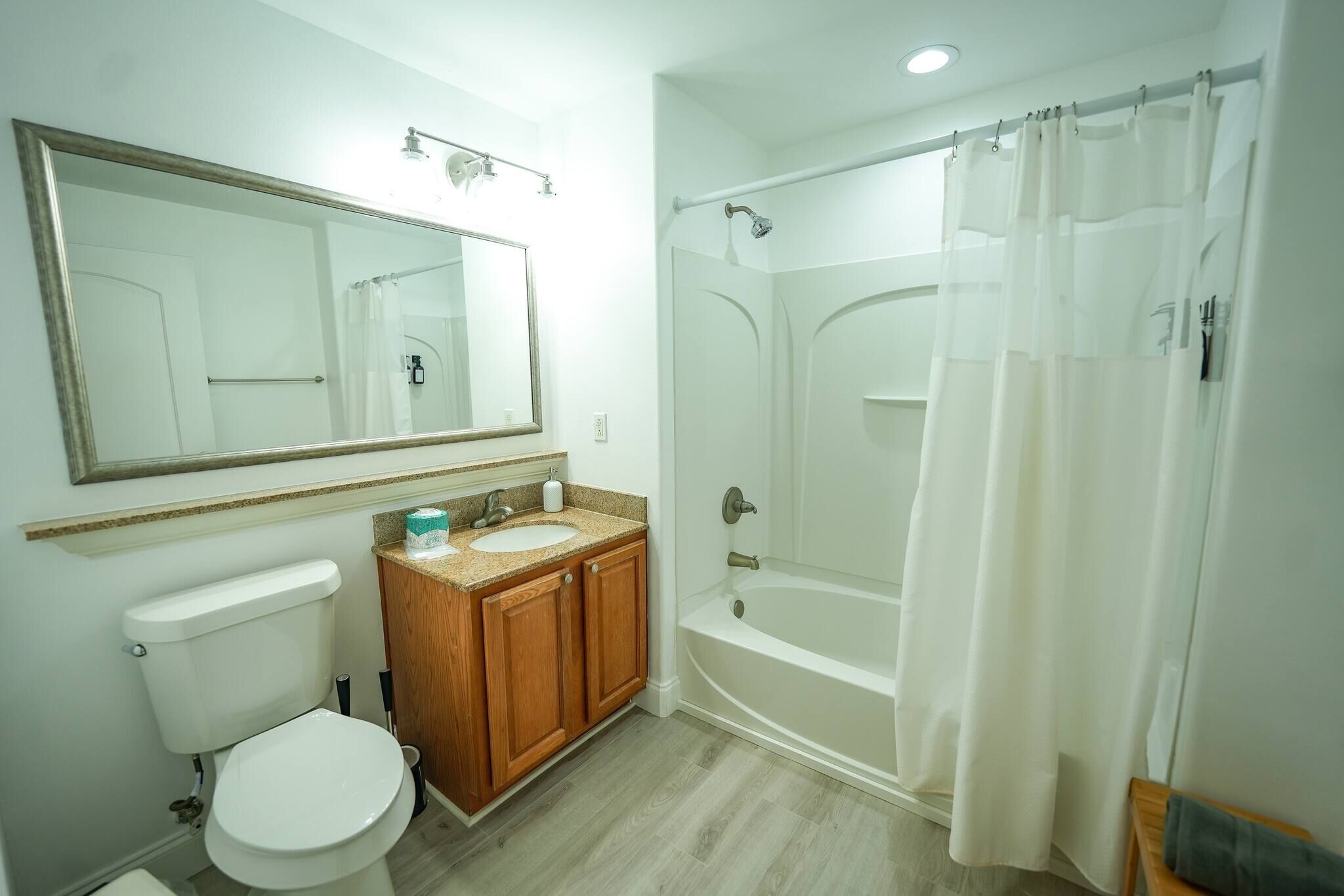 A bathroom with a toilet, sink, mirror, shower, and bathtub.