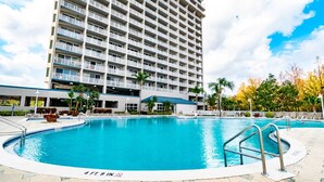 A swimming pool with a 4ft 9in depth marker, surrounded by a tiled deck, with a high-rise building in the background. - Orlando Blue Heron Condo 1 Mile From Disney 10th f (Orlando)