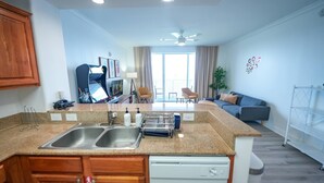 A modern kitchen with a dishwasher, double sink, and a dining area with a sofa and chairs. - Orlando Blue Heron Condo 1 Mile From Disney 10th f (Orlando)