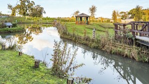 Un cadre paisible au bord du lac, avec un belvédère, une terrasse en bois et une petite maison située au bord de l’eau.