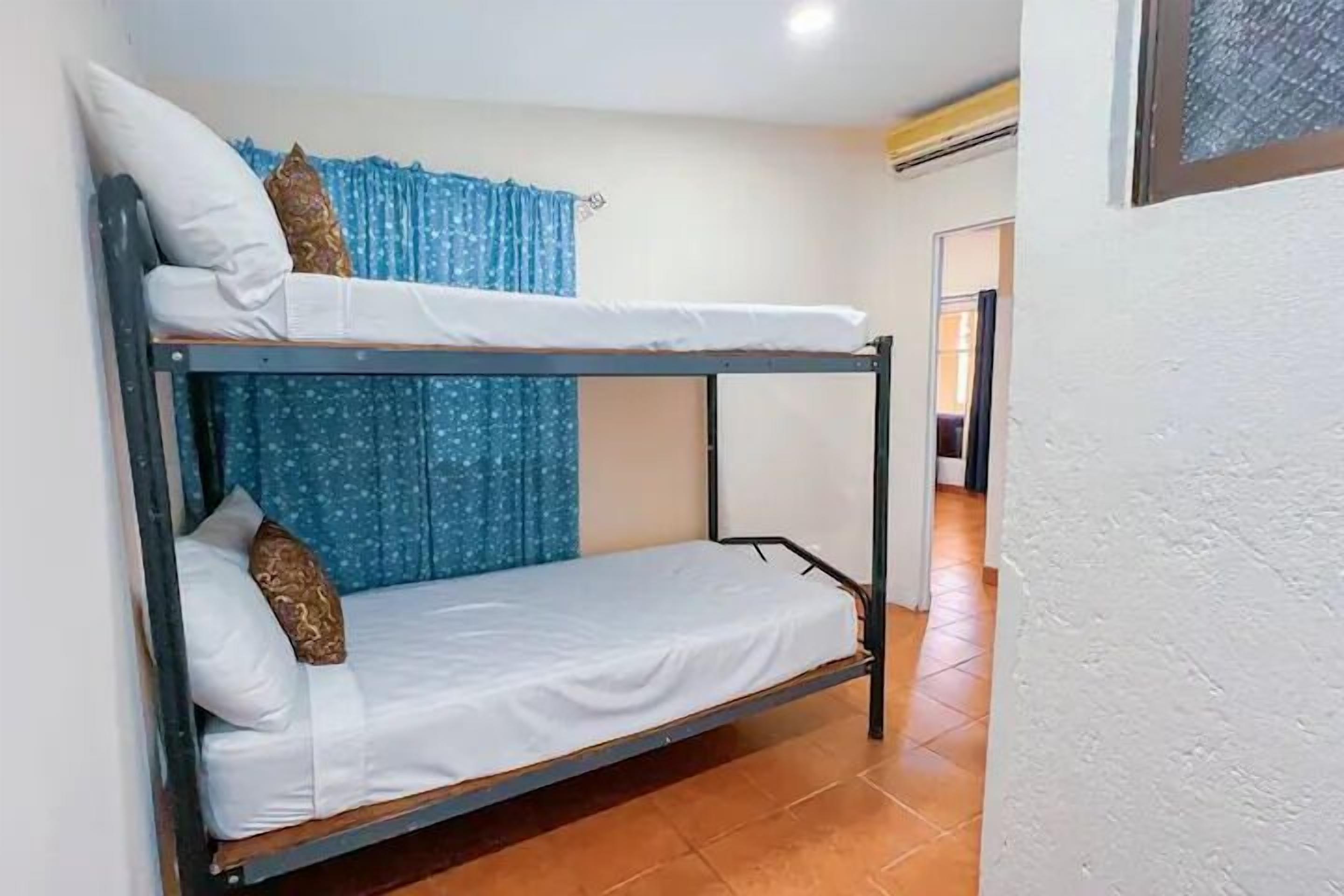A bunk bed room with a blue curtain and a white wall.