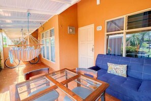 Relax in this inviting room with a blue sofa, glass-top coffee table, and hammock, offering a peaceful atmosphere.