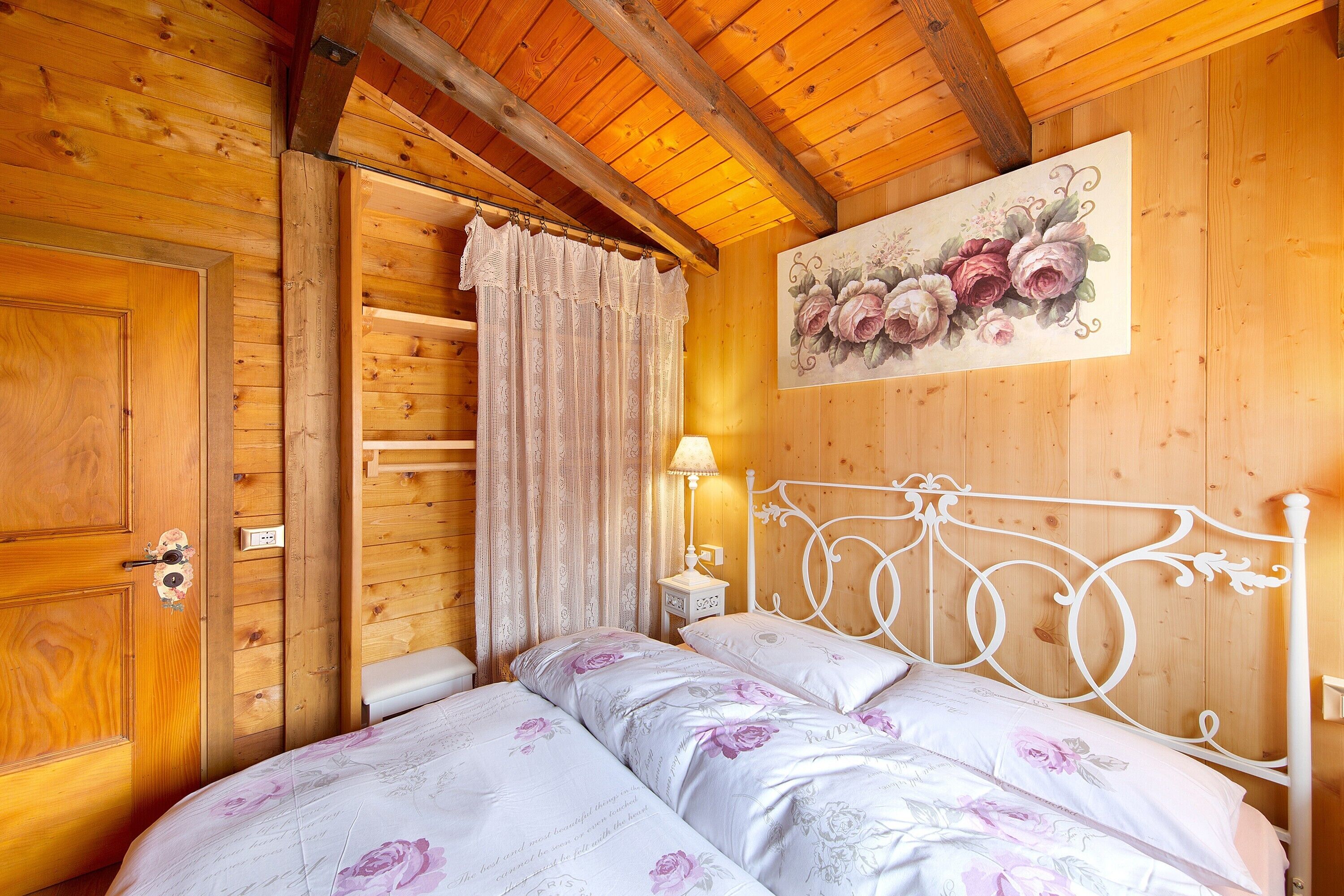 Una habitación de madera con una cama, una mesita de noche, una lámpara y una puerta.