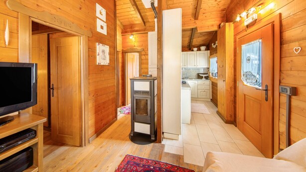 Un interior de madera con televisor, chimenea y zona de cocina.