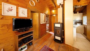 A wooden interior with a television, a fireplace, and a kitchen area.