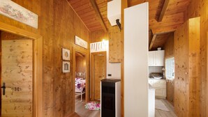 Een houten interieur met een bed, een kachel en een kitchenette.