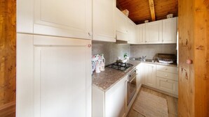 Een keuken met witte kastjes, een granieten aanrechtblad, een gasfornuis en een houten plafond.