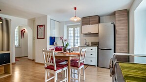 Een moderne keuken met houten kastjes, een roestvrijstalen koelkast en een eethoek met een houten tafel en stoelen.