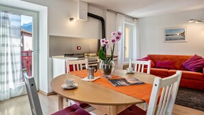 Een eethoek met een tafel, stoelen, een koffiepot en een vaas met bloemen.