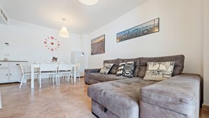 Un salon moderne avec un canapé, une table à manger, des chaises et une horloge au mur.