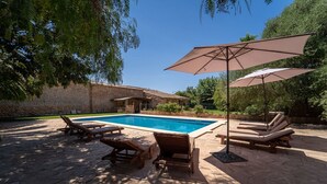 A swimming pool with lounge chairs and umbrellas, surrounded by stone walls and greenery. - Country House 'Cugulutx' with Private Pool, Private Terrace and Wi-Fi (Llucmajor)