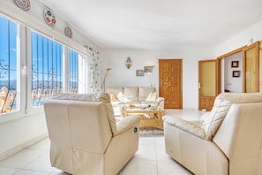 A living room with a sofa, armchairs, a coffee table, and a view of the outdoors. - Villa 'Casasilma' with Sea View, Wi-Fi and Air Conditioning (POBLE NOU DE BENITATXELL)