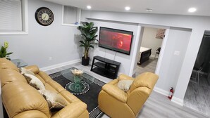 A modern living room with a sofa set, a coffee table, and a flat-screen TV mounted on the wall.
