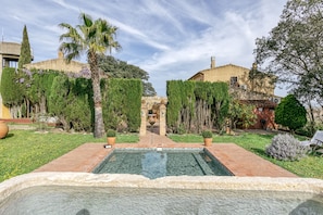 A swimming pool with a tiled deck, surrounded by greenery and buildings. - Apartment 'El Pedró Rural' with Mountain View, Wi-Fi and Air Conditioning (Ventalló)