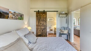 Un dormitorio con cama, una puerta de madera, un baño y vistas al exterior.