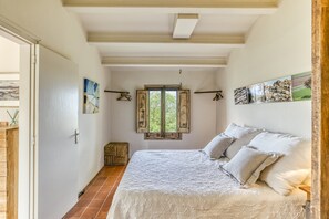 A bedroom with a bed, a window, and a door.