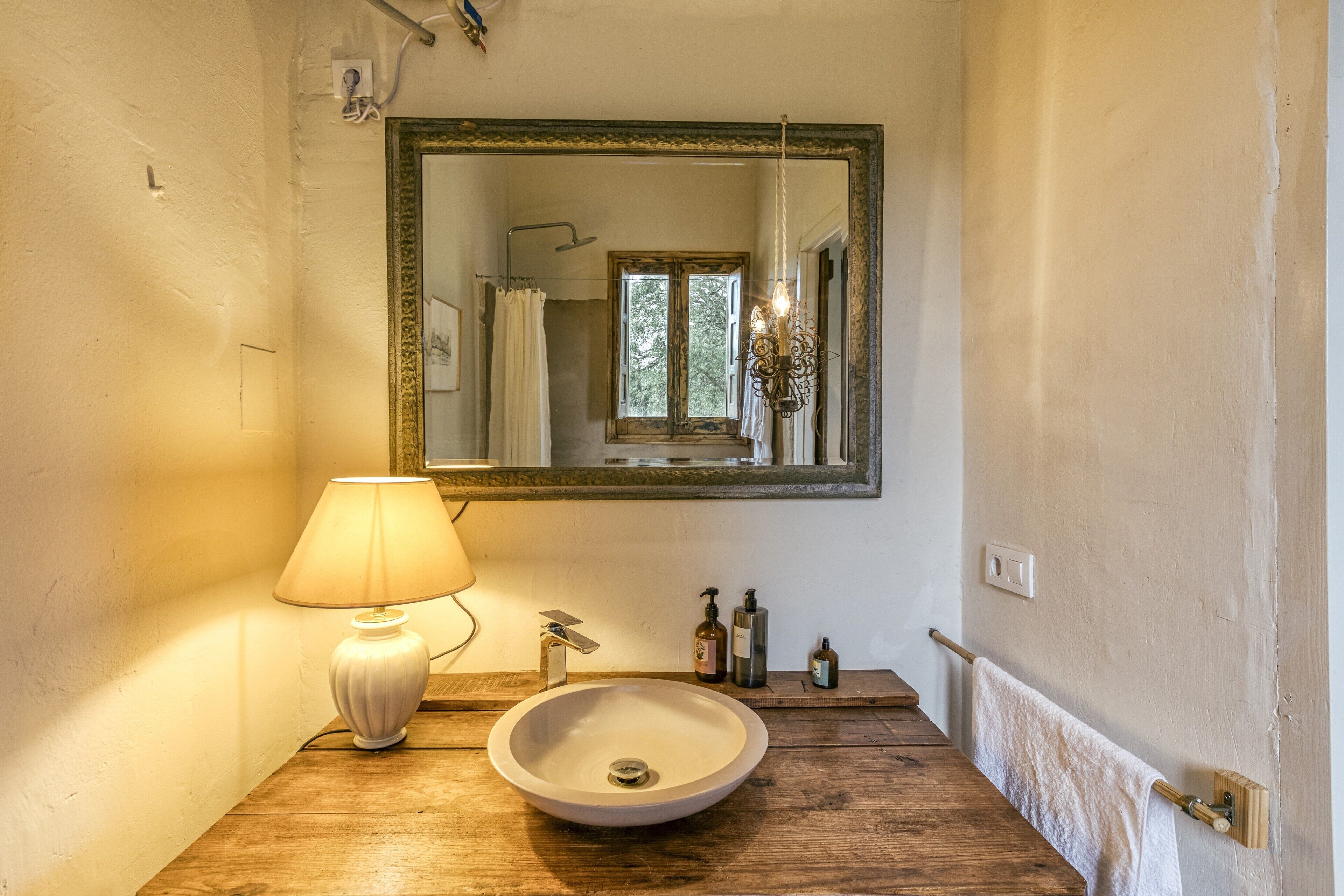A bathroom with a wooden vanity, a white sink, a mirror, a hanging light, and a towel rack.