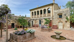 Un patio con un edificio de piedra, una fuente y plantas en macetas.
