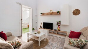 Una sala de estar con televisión, sofá, mesa de centro y puerta que da a un balcón.