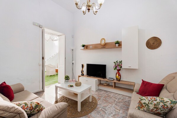 Un salon équipé d ’un téléviseur, d’un canapé, d’une table basse et d’une porte donnant sur un balcon.