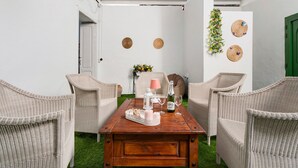 Una habitación con mobiliario de mimbre, una mesa de centro de madera y una puerta verde.