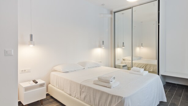 Une chambre d’hôtel moderne, équipée d’un lit, d’une table de chevet et d’un grand miroir.